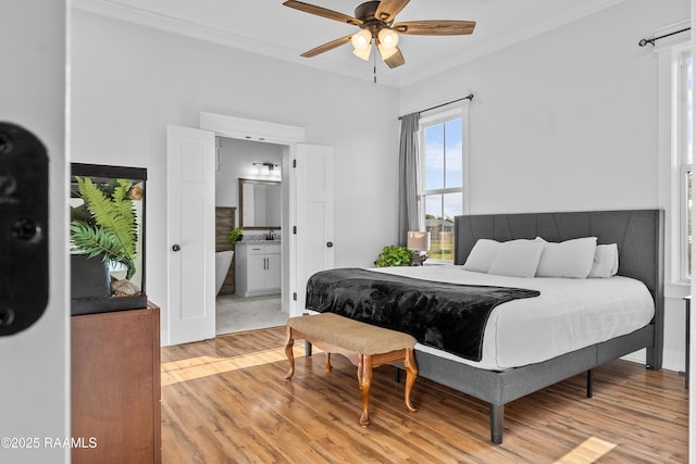 bedroom featuring a sink, ornamental molding, a ceiling fan, light wood finished floors, and ensuite bath