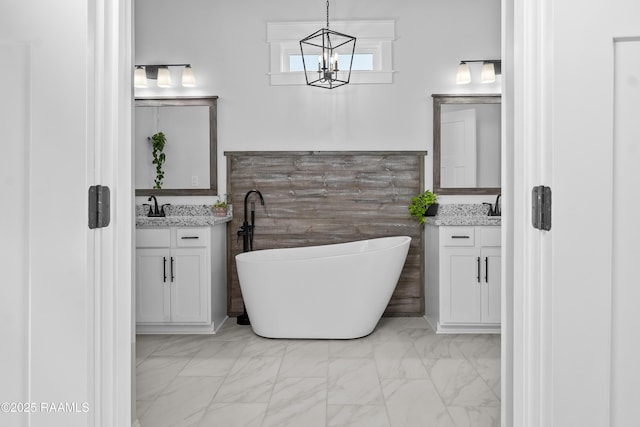 full bathroom featuring a sink, two vanities, a freestanding bath, and marble finish floor