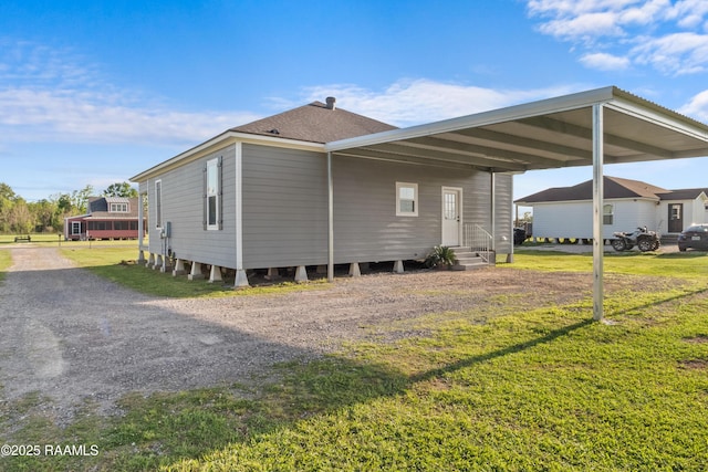 view of property exterior featuring a yard, roof with shingles, entry steps, and driveway