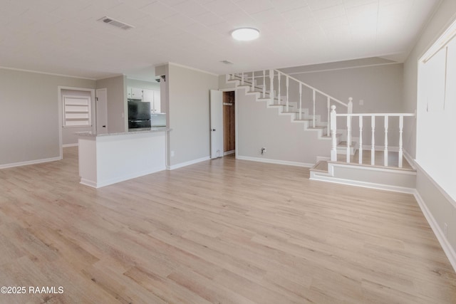 unfurnished living room with stairway, visible vents, baseboards, and light wood-style flooring