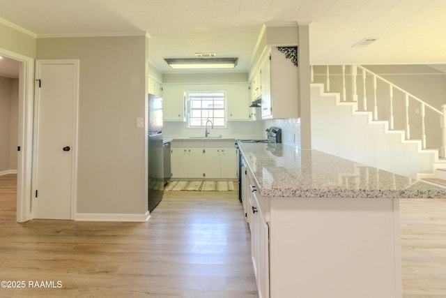 kitchen with a sink, ornamental molding, appliances with stainless steel finishes, light wood-type flooring, and light stone counters