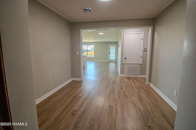 hallway featuring visible vents, baseboards, ornamental molding, and wood finished floors