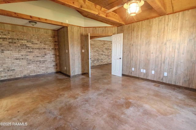 spare room with baseboards, brick wall, finished concrete flooring, wood walls, and vaulted ceiling with beams