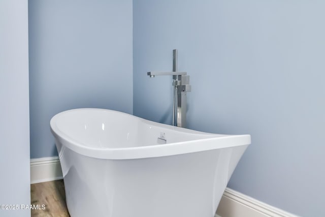 bathroom featuring wood finished floors and a freestanding bath
