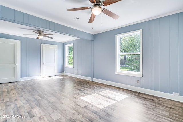 spare room with wood finished floors, baseboards, a ceiling fan, and crown molding