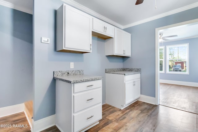 kitchen with baseboards, white cabinetry, a ceiling fan, wood finished floors, and ornamental molding