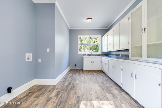 clothes washing area with crown molding, hookup for a washing machine, cabinet space, light wood-style flooring, and baseboards