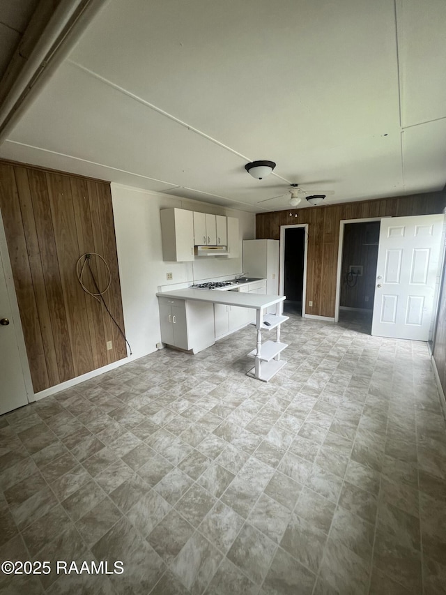 1009/1011 Providence St, New Iberia, LA 70560 - kitchen featuring light countertops, a ceiling fan, freestanding refrigerator, wood walls, and a breakfast bar area