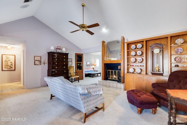 living room with ceiling fan, high vaulted ceiling, light colored carpet, visible vents, and a tile fireplace