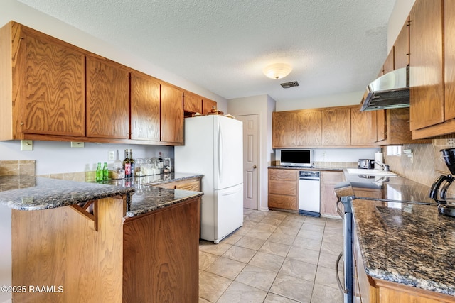 kitchen with freestanding refrigerator, stainless steel electric stove, a peninsula, visible vents, and under cabinet range hood