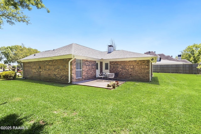 back of property featuring a lawn, a patio area, fence, and brick siding