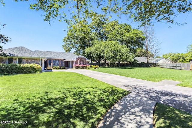ranch-style home featuring brick siding, fence, and a front lawn