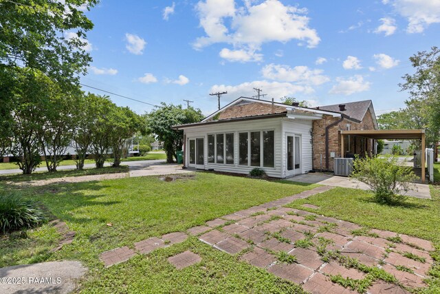 311 S Morgan Ave, Broussard, LA 70518 - back of property featuring a patio, cooling unit, a lawn, a carport, and brick siding