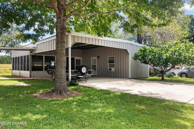 back of house with a carport, a yard, board and batten siding, and concrete driveway