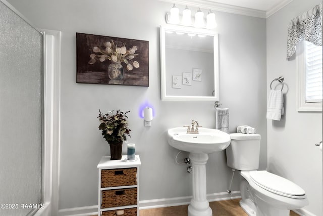 bathroom with baseboards, walk in shower, a sink, toilet, and crown molding