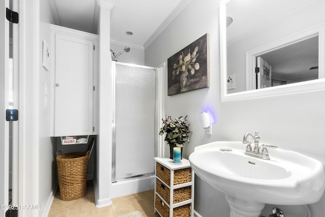 bathroom featuring a shower stall, a sink, ornamental molding, and tile patterned flooring