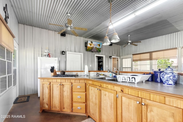 kitchen featuring a sink, a ceiling fan, tile counters, finished concrete flooring, and gas cooktop