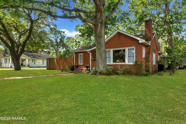 1703 W University Ave, Lafayette, LA 70506 - view of front facade with brick siding, a front lawn, fence, and a chimney