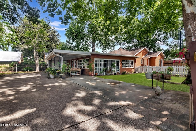 1703 W University Ave, Lafayette, LA 70506 - view of front of home featuring fence, a front yard, driveway, and brick siding