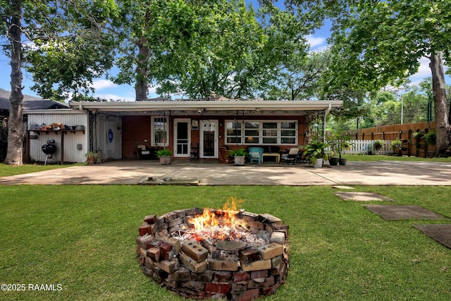 1703 W University Ave, Lafayette, LA 70506 - rear view of house with a lawn, fence, a patio, and a fire pit