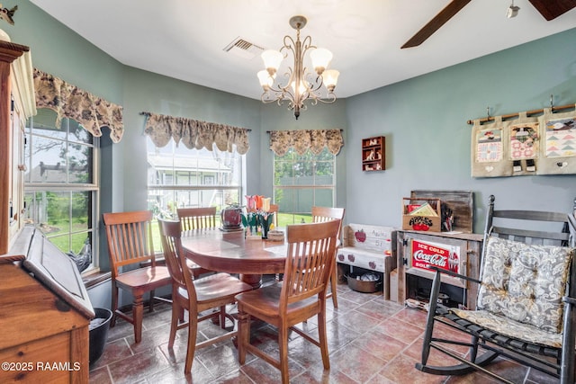 dining area with stone finish flooring, ceiling fan with notable chandelier, visible vents, and a wealth of natural light
