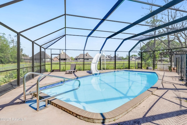 pool with a water slide, glass enclosure, a patio, fence, and a residential view