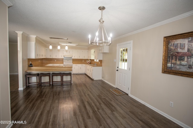 140 Saint Leo St, Opelousas, LA 70570 - unfurnished dining area with baseboards, a notable chandelier, dark wood finished floors, crown molding, and rail lighting