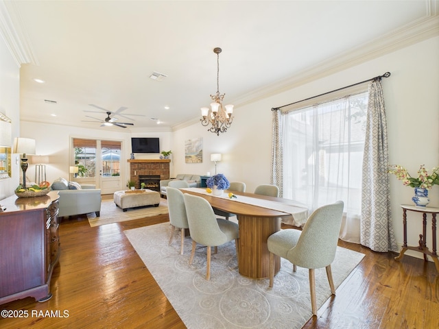 111 Croft Row, Lafayette, LA 70503 - dining space featuring a fireplace, ceiling fan with notable chandelier, wood finished floors, visible vents, and ornamental molding
