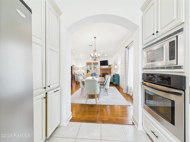 111 Croft Row, Lafayette, LA 70503 - kitchen featuring arched walkways, a chandelier, stainless steel appliances, light tile patterned floors, and ornamental molding