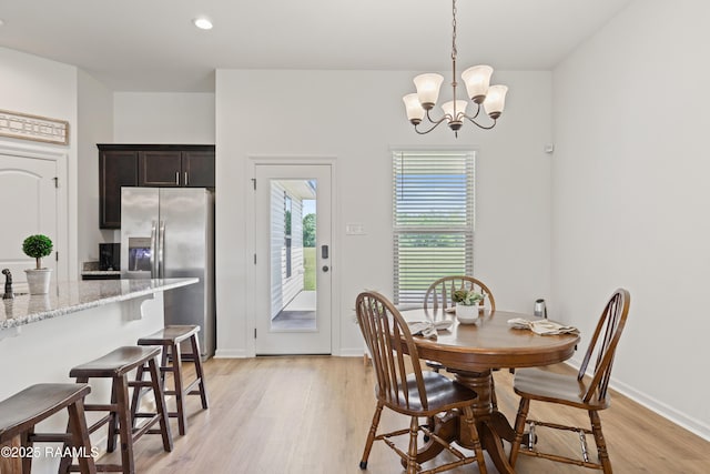 dining space featuring baseboards, light wood finished floors, an inviting chandelier, and recessed lighting