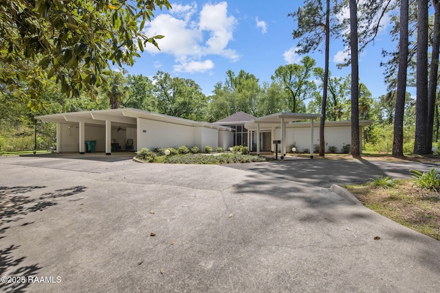 mid-century home with a carport, ceiling fan, driveway, and stucco siding