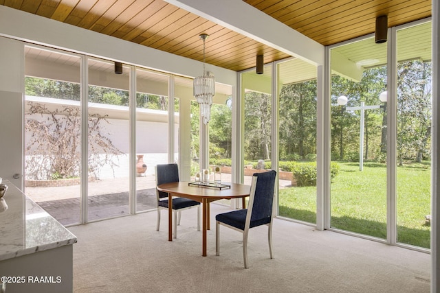 sunroom / solarium with beamed ceiling, outdoor dining space, an inviting chandelier, and a healthy amount of sunlight
