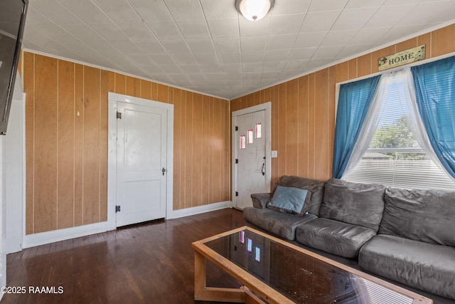 living room with wooden walls, baseboards, ornamental molding, and wood finished floors
