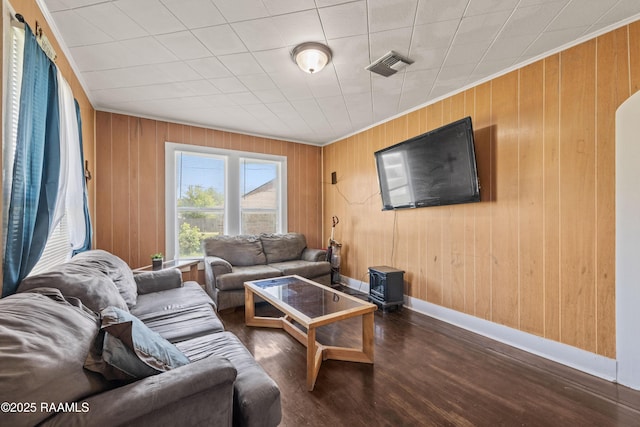 living room with ornamental molding, visible vents, wood finished floors, and wood walls
