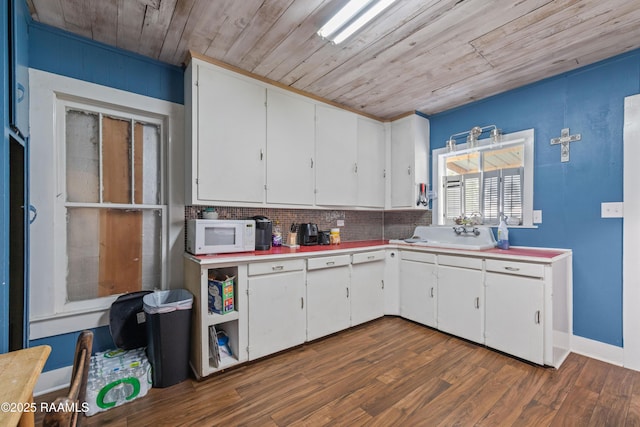 kitchen featuring a sink, light countertops, wood ceiling, white microwave, and white cabinetry