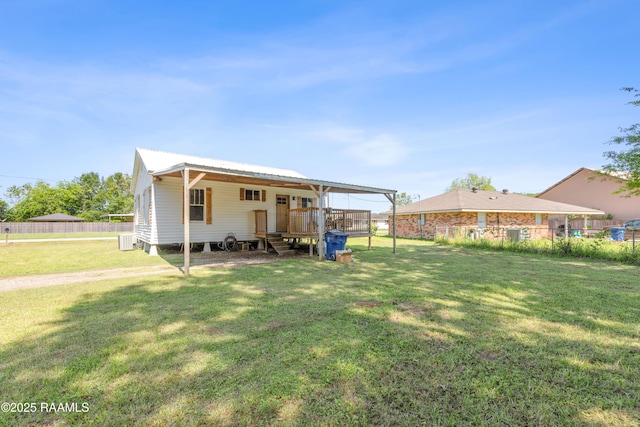 back of property with central AC, a deck, a yard, metal roof, and fence
