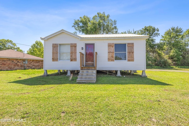 manufactured / mobile home with metal roof, entry steps, and a front lawn