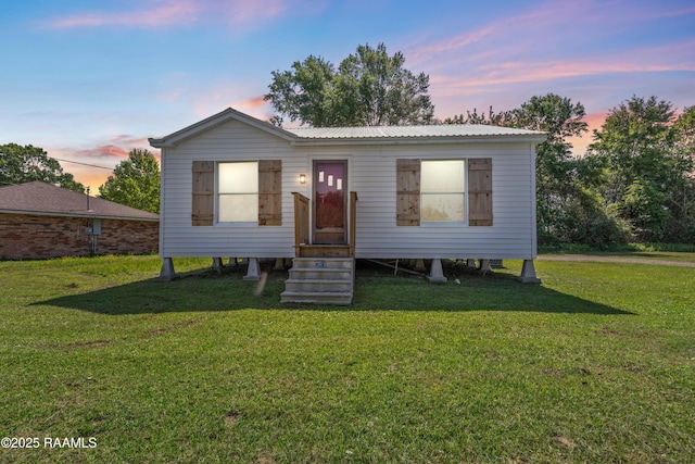 manufactured / mobile home featuring entry steps, metal roof, and a lawn
