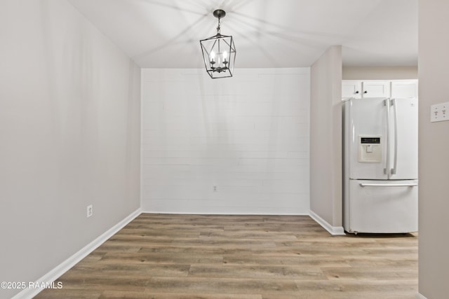 701 S College Rd Unit 303, Lafayette, LA 70503 - unfurnished dining area with light wood-style flooring, an inviting chandelier, and baseboards