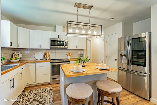 kitchen with light wood-style flooring, visible vents, white cabinetry, wooden counters, and appliances with stainless steel finishes