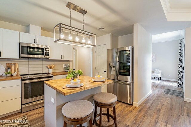 kitchen featuring white cabinets, appliances with stainless steel finishes, butcher block countertops, and visible vents