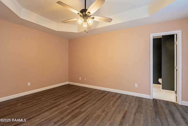 spare room featuring a tray ceiling, dark wood-style floors, baseboards, ceiling fan, and ornamental molding