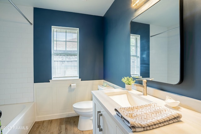 full bathroom featuring wood finished floors, toilet, vanity, and wainscoting
