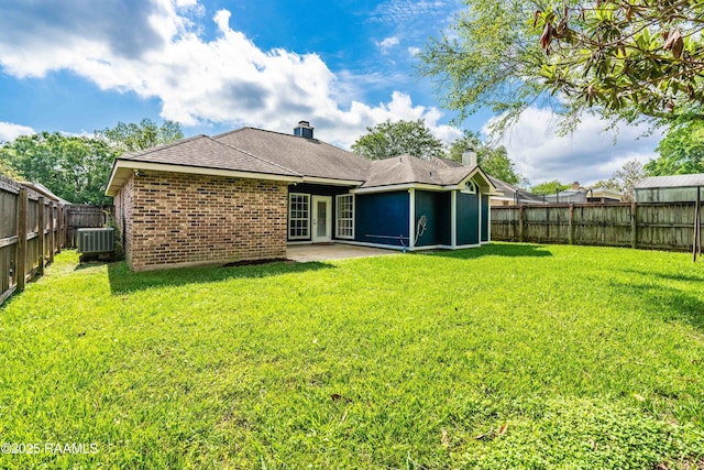 rear view of house featuring central AC, brick siding, a fenced backyard, and a lawn
