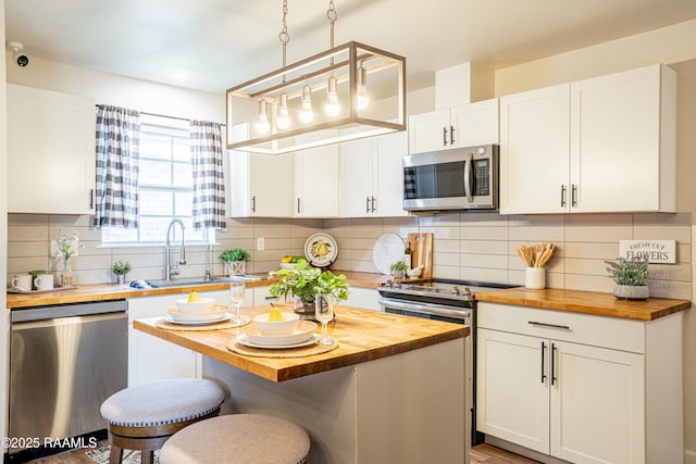 kitchen with wood counters, appliances with stainless steel finishes, and white cabinets