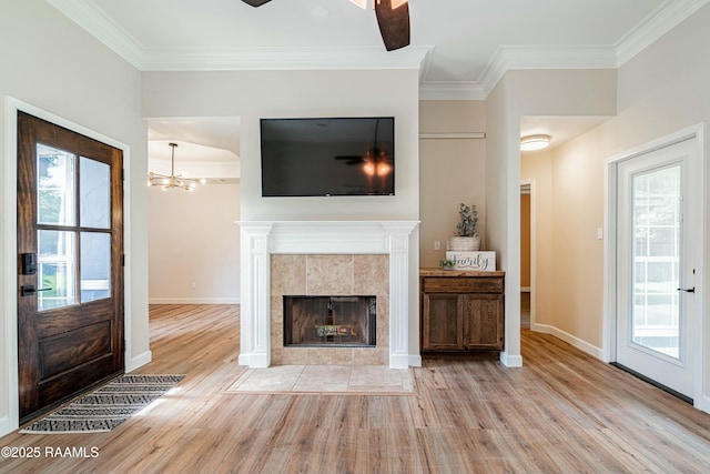 living area with light wood-style floors, baseboards, ornamental molding, and ceiling fan with notable chandelier