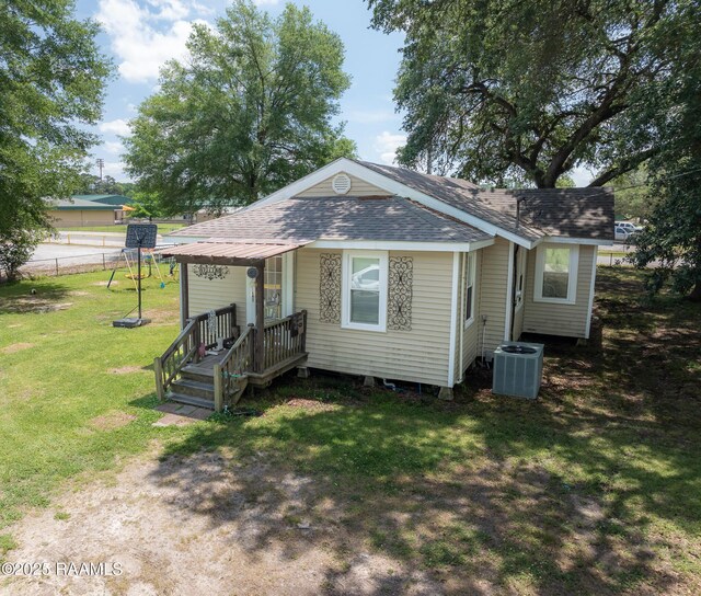 1207 Oak St, Ville Platte, LA 70586 - bungalow with central air condition unit, fence, roof with shingles, and a front lawn