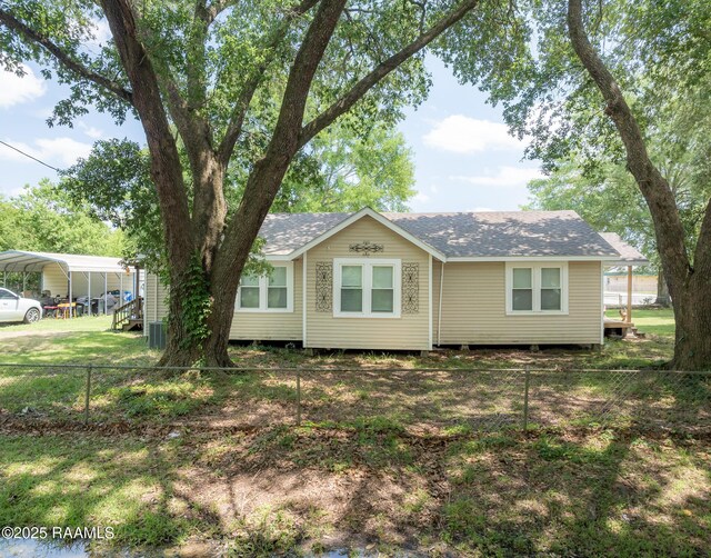 1207 Oak St, Ville Platte, LA 70586 - view of front facade featuring cooling unit, roof with shingles, fence, and a carport