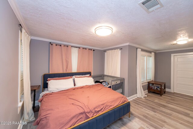 1207 Oak St, Ville Platte, LA 70586 - bedroom featuring a textured ceiling, visible vents, crown molding, wood finished floors, and baseboards