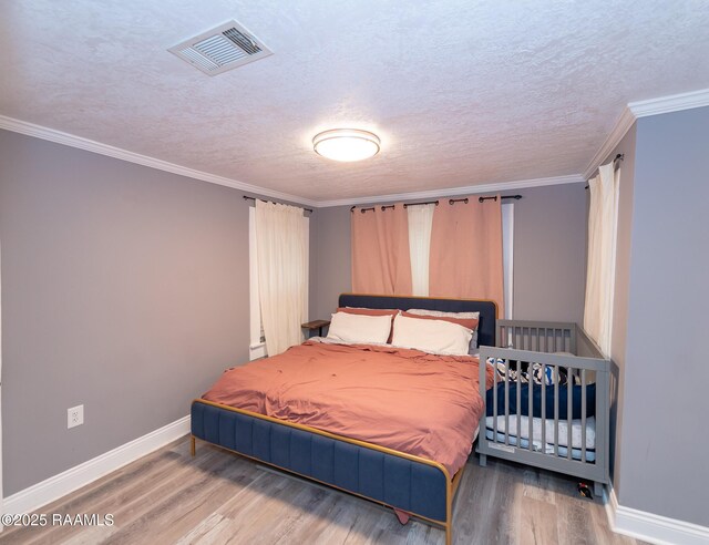 1207 Oak St, Ville Platte, LA 70586 - bedroom with a textured ceiling, baseboards, wood finished floors, visible vents, and ornamental molding